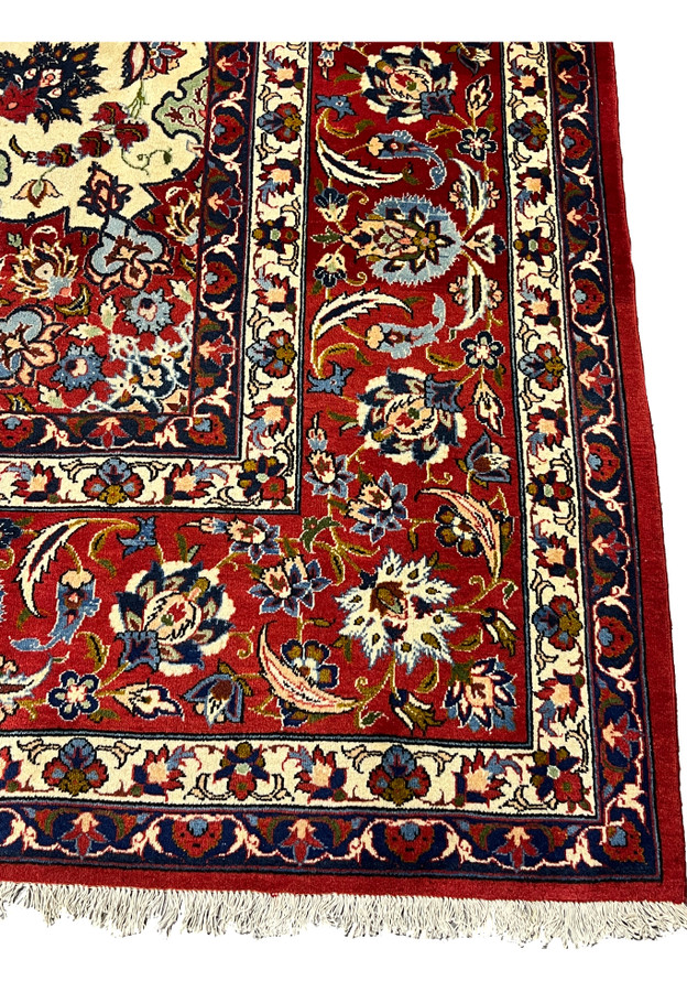 Detailed view of the main border on a Persian Isfahan rug showcasing rich red background, floral arabesques, and precise hand-knotted construction