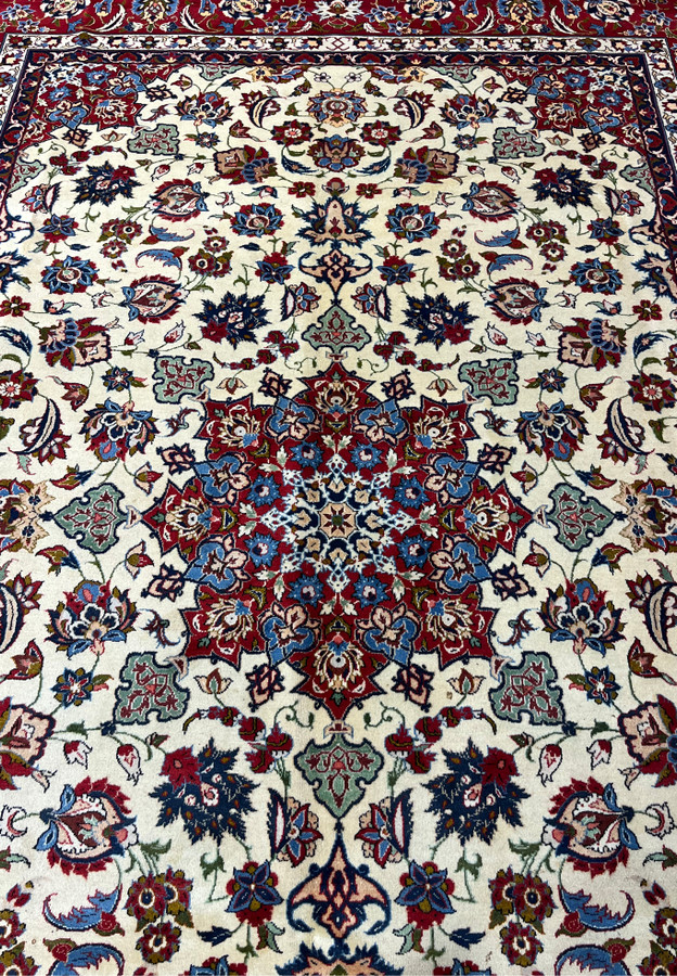 Close view of the central field of a Persian Isfahan rug highlighting detailed floral motifs, silk accents, soft ivory tones, and precise kork wool knotting