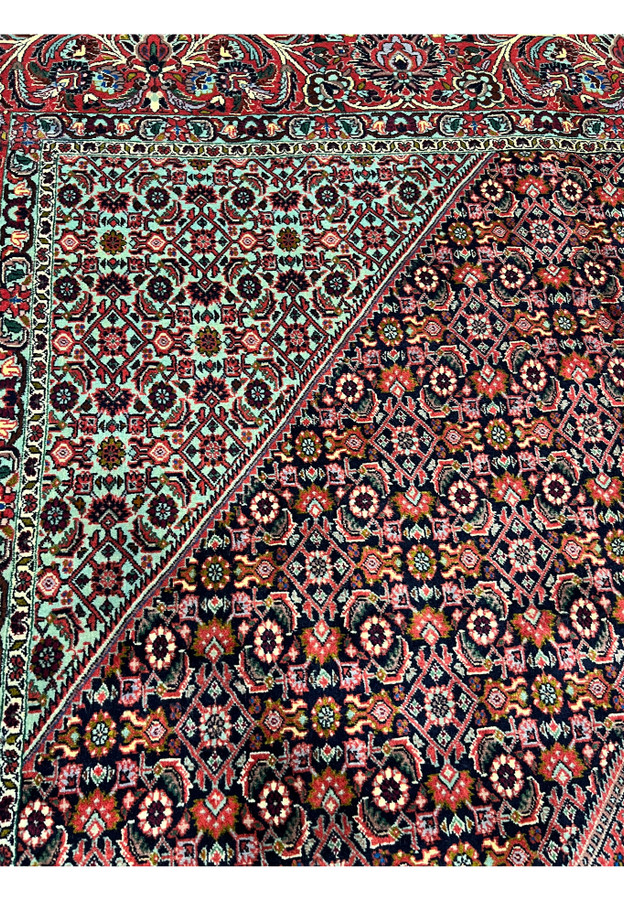 Color detail closeup of a Persian Bijar rug showing deep red, navy blue, ivory, olive green, and subtle light blue tones woven into dense wool