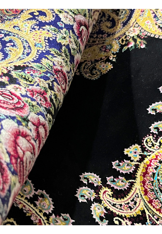 Zoomed rolled detail of a signed Persian Qum pure silk rug highlighting fine pile and dense knot structure