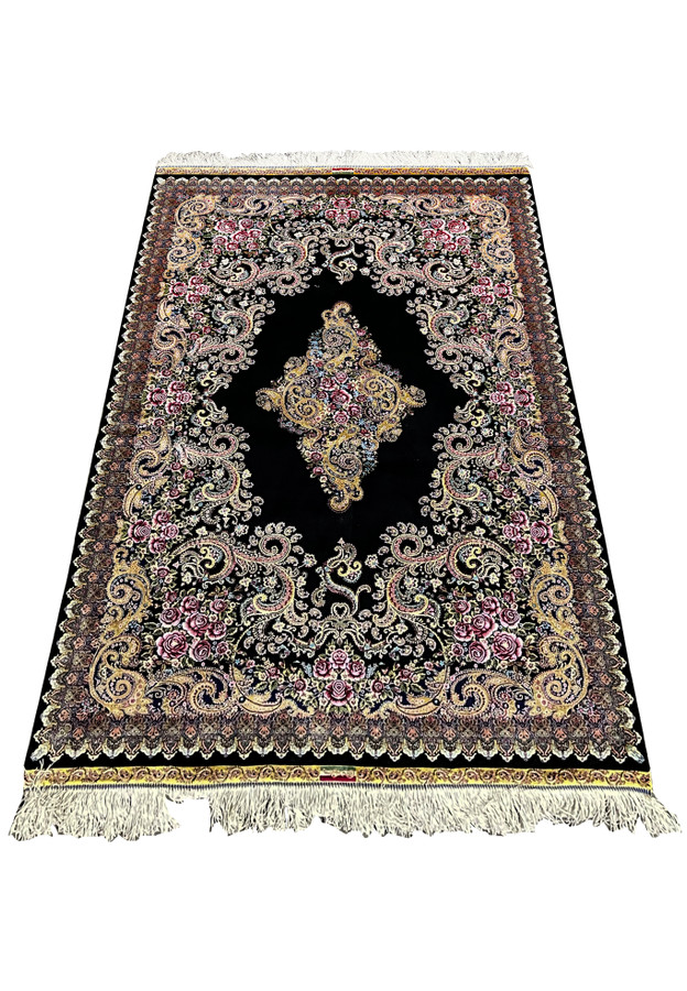 Full laid-down view of a signed Persian Qum pure silk rug with black field, floral medallion, and intricate rose motifs