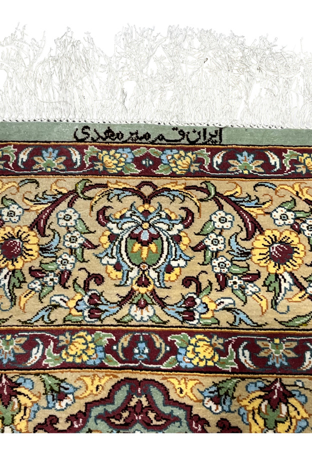Signed end of a Persian Qum pure silk rug showing Mirmehdi signature above the border with fine ivory silk fringe.