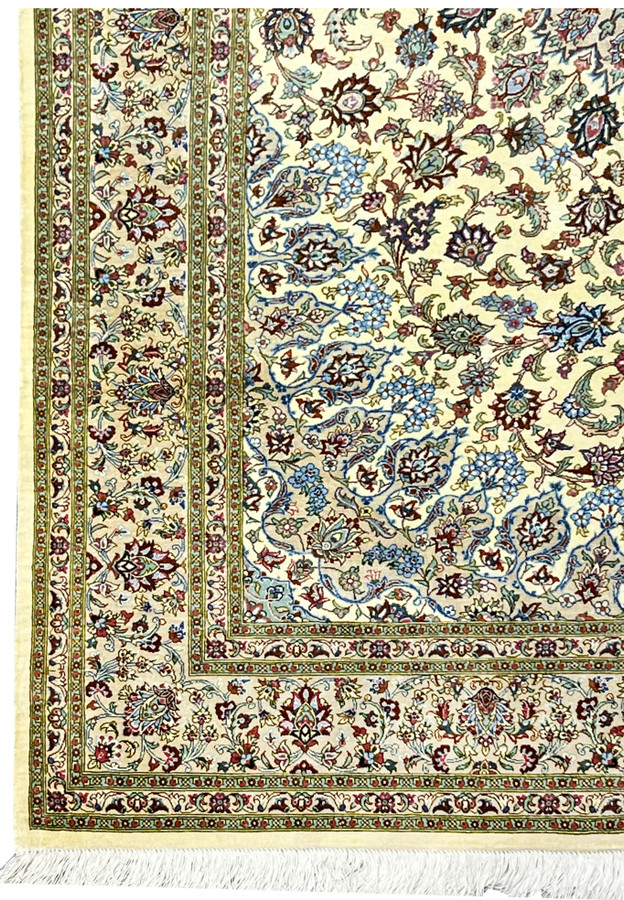 Detailed border view of a signed Persian Qum silk rug featuring continuous floral cartouches, precise outlines, and harmonious color balance along the ivory frame.