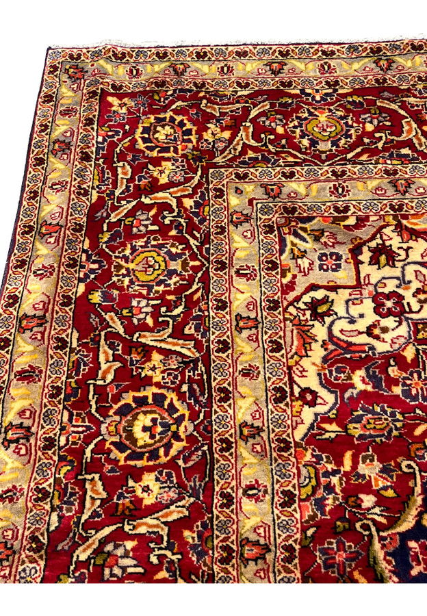Upper border detail of Persian Isfahan rug showcasing repeating floral cartouches, brick red ground, and ivory guard borders
