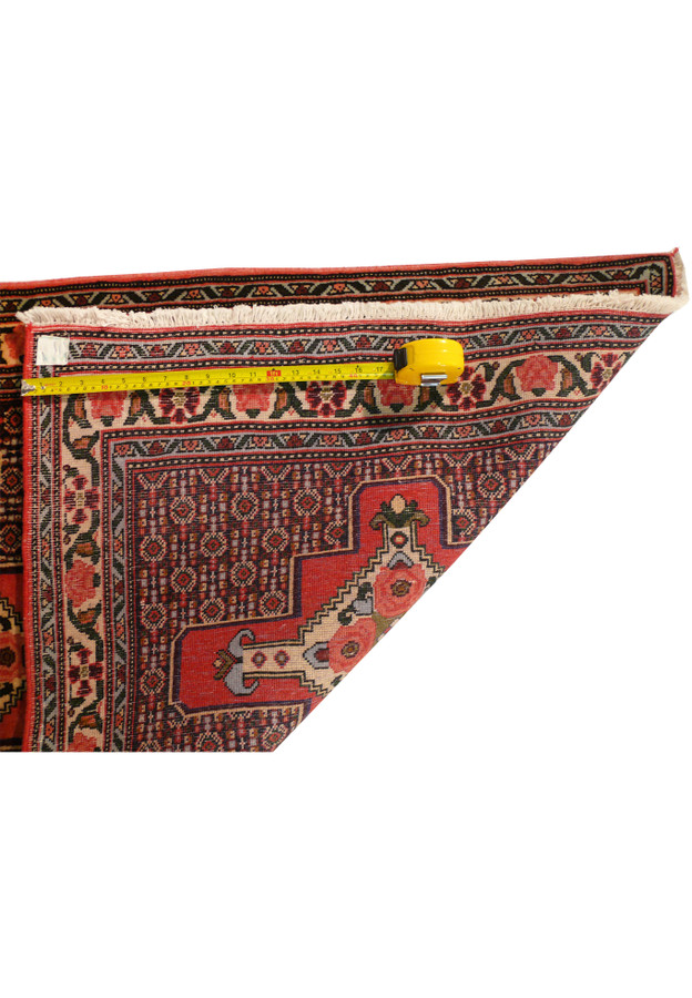 Corner fold of Senneh rug displaying pile height structure wool foundation and clean edges with fringe