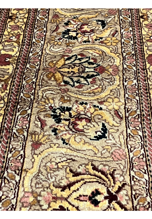 Closeup of Agra rug border with floral cartouches, beige tan ground, burgundy and gold accents, showing detailed hand knotted wool texture