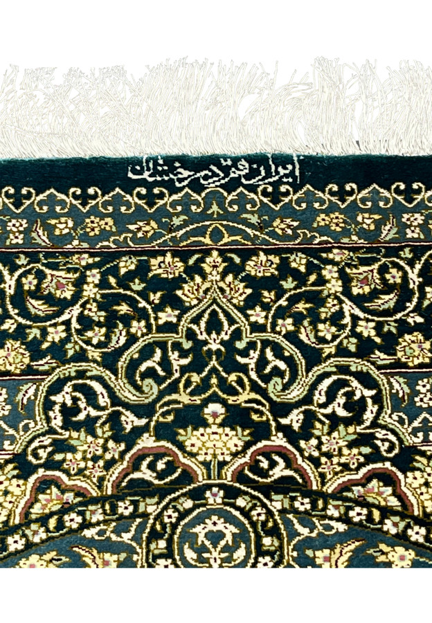 Close view of Darakhshan signature woven in silk along border with ivory script on teal background