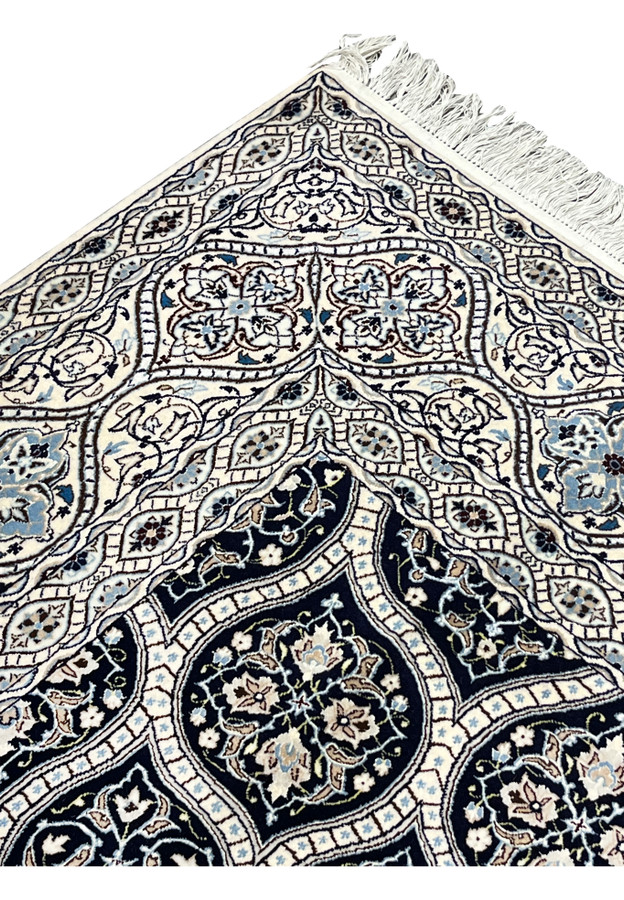 Upper edge detail of Persian Nain 6 LA rug with ivory fringe navy border and light blue floral guard stripes.