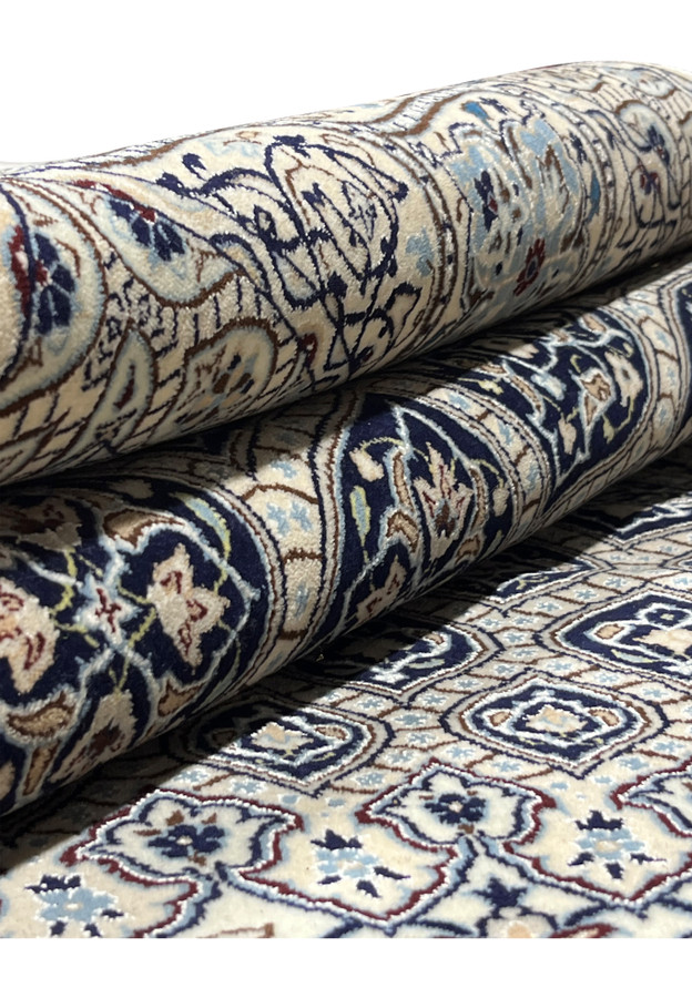 Rolled 6'9 x 10 Persian Nain Habibian 6 LA Kork and silk rug showing ivory field navy Gombadi dome pattern and tight pile.