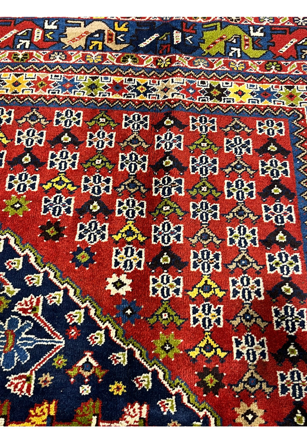 Hand knotted Persian Yalameh rug motif detail featuring tribal medallions floral elements and rich navy blue field