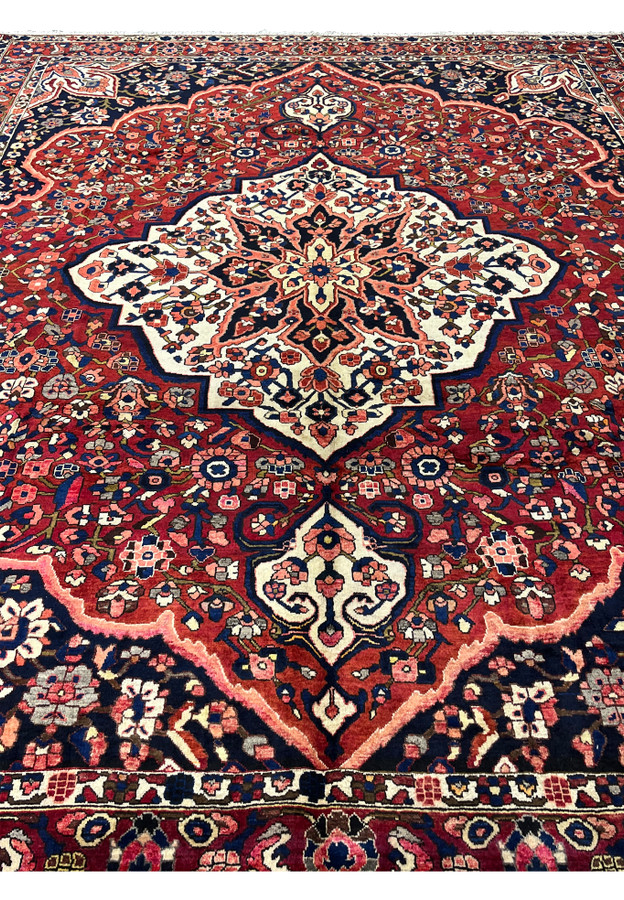 Midfield detail of vintage Persian Bakhtiari rug showing dense hand-knotted floral pattern on crimson ground