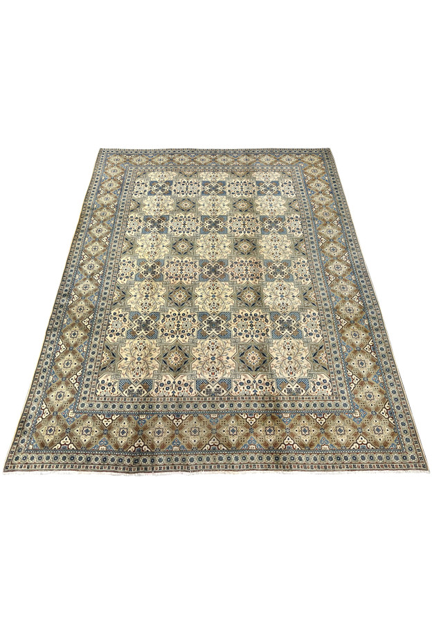 Perspective view of a large hand-knotted Tabriz rug laid flat on a white surface, showcasing the full proportions of the 9’8 x 13 carpet with its all-over panel design, multi-band border, and short cotton fringe at both ends.