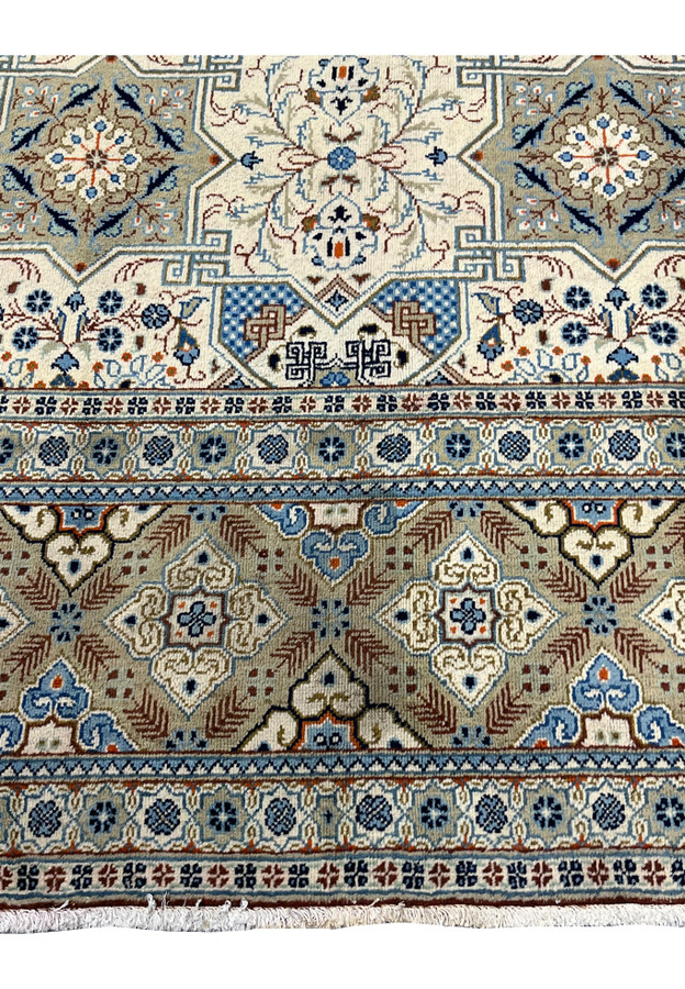 Close-up of the lower border and field junction of a Persian Tabriz rug, displaying the transition from the eight-pointed star design to the multi-band border with diamond cartouches, palmette scrollwork, and short cotton fringe.