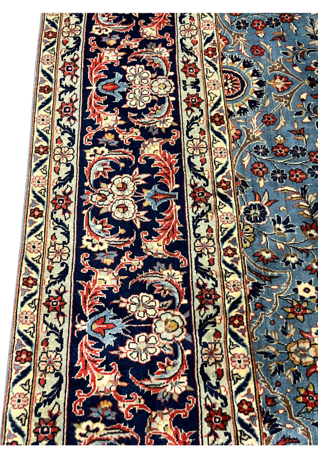 Persian Kashan rug 8x12 navy border closeup with scrolling floral arabesques and vines