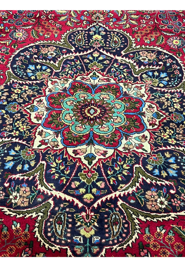 Medallion closeup of 10x13 Persian Tabriz rug, eight-petal floral rosette with teal and crimson