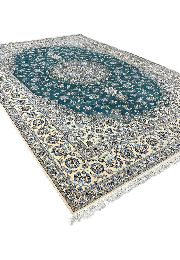 Jewel-toned emerald green Nain rug angled view showing silk highlights catching the light across the floral field