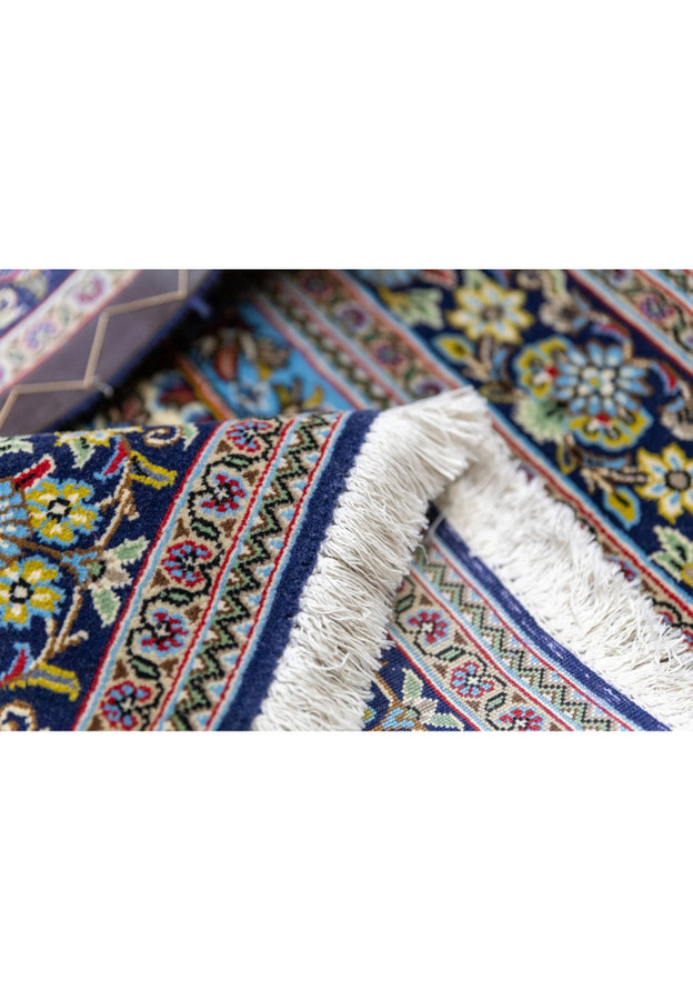 Close-up of indigo medallion with golden yellow palmettes and crimson red accents on Persian Qum kork rug