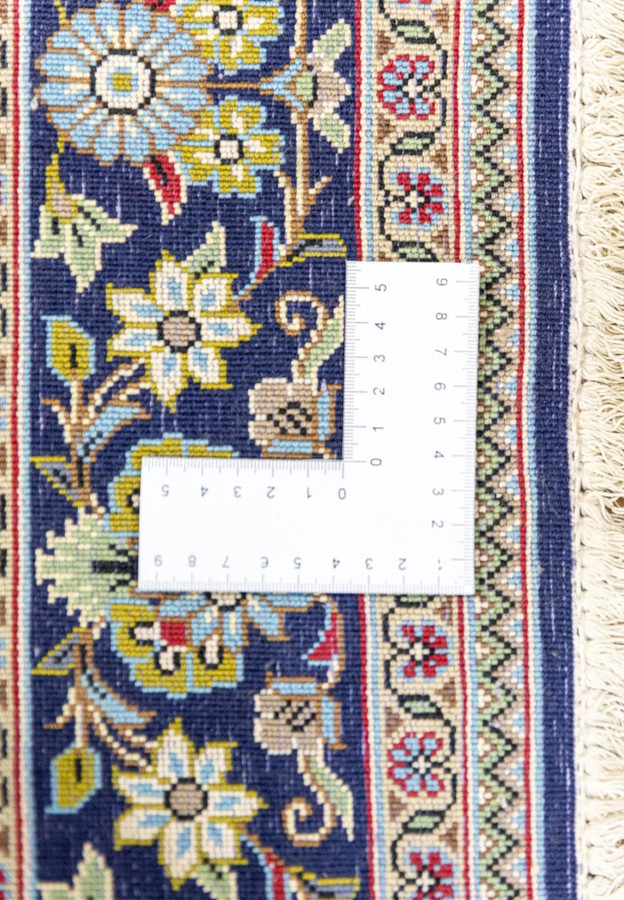 Backside of Persian Qum rug measured at 400 knots per square inch with ruler showing dense fine weave