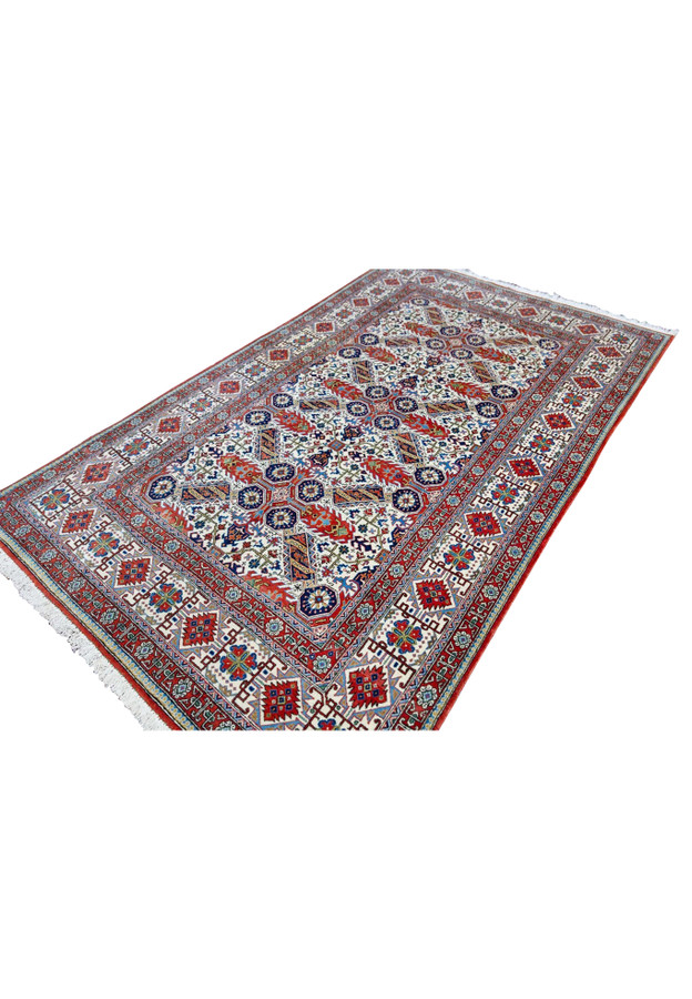Persian Qum kork wool rug angled view showing geometric octagonal stars and brick red border on ivory ground