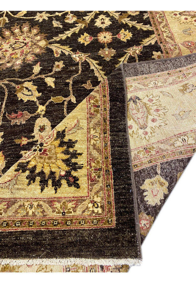 Folded corner of Agra rug showing black field, gold border, and red minor guard stripe transition