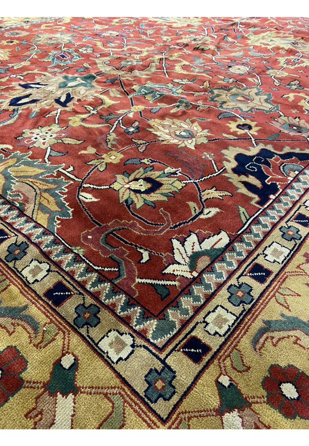 Inner sawtooth and rosette guard borders framing the soft red field of an authentic Indo Agra rug