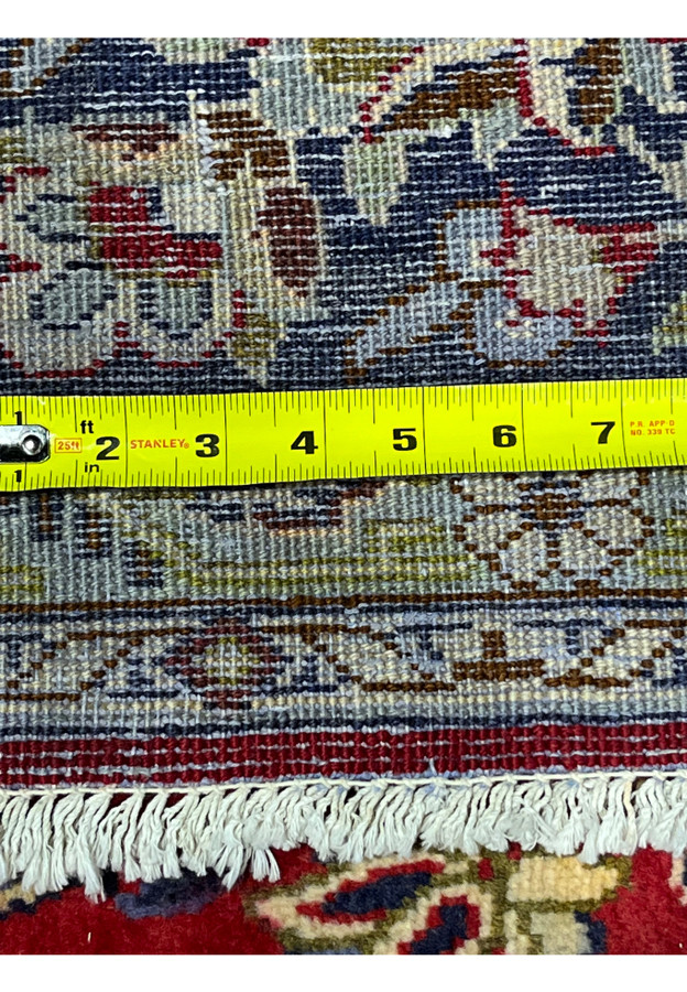 Tape measure across the rug back documenting the fine knot density that places this Isfahan in workshop quality range