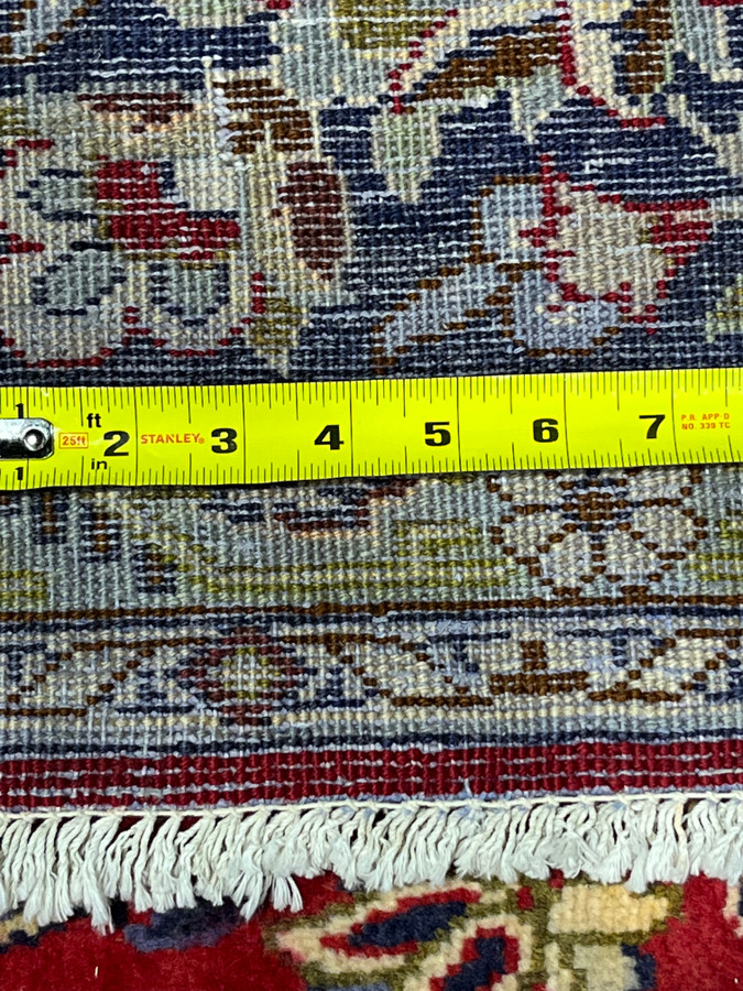 Tape measure across backside of Persian Isfahan rug confirming approximately 200 to 220 KPSI hand knotting