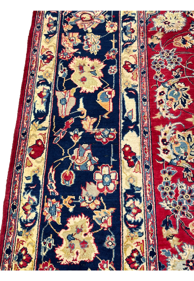Inner border closeup of Persian Isfahan rug showing scrolling vine and rosette palmettes on navy ground