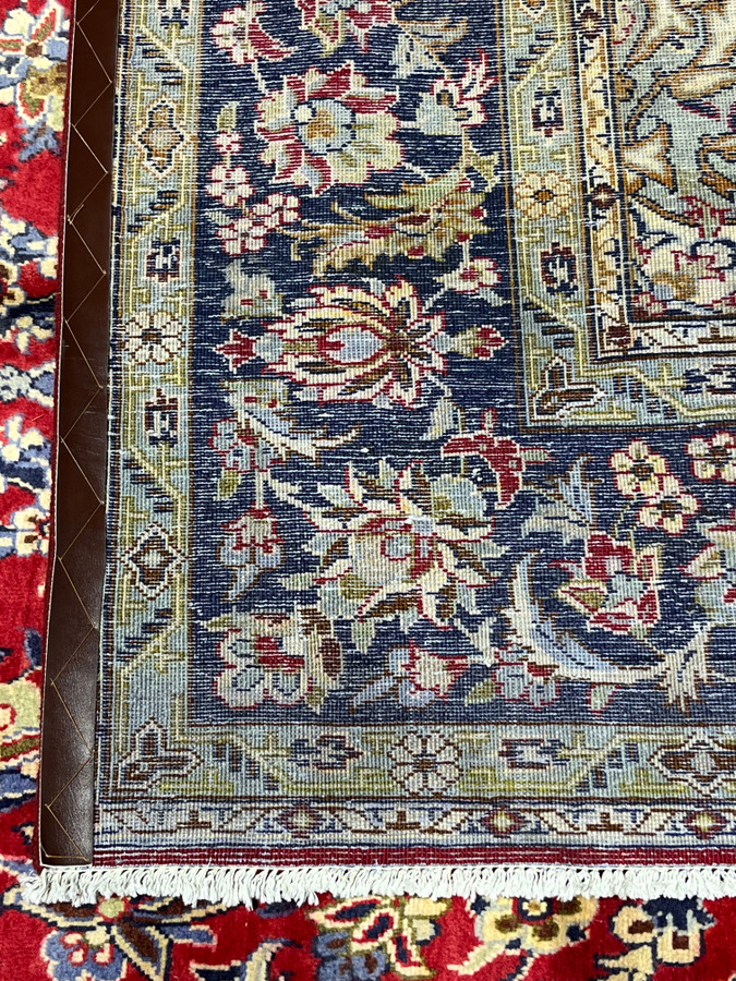 Backside corner of authentic Persian Isfahan rug showing dense knot structure on cotton foundation