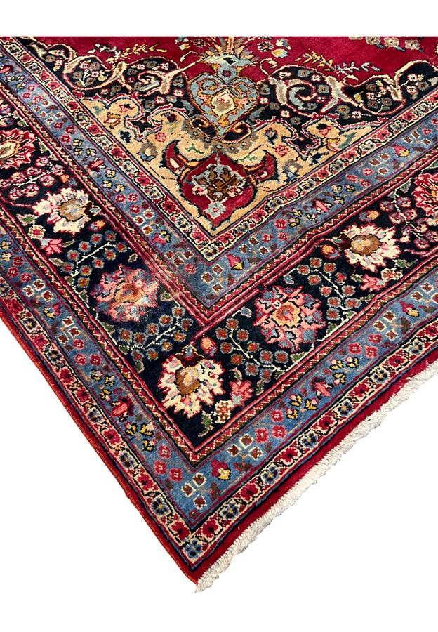 Corner detail of handmade Persian Kerman rug for dining room showing ivory spandrel, navy border, and crimson field junction