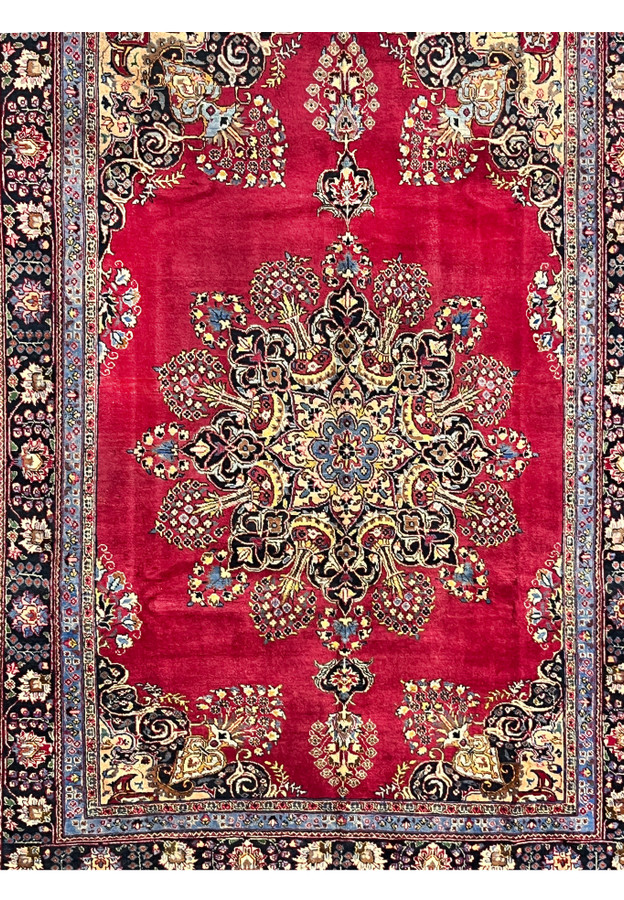 Closeup of Persian Kerman midfield showing the lobed sunburst medallion radiating into bouquet sprays on deep red ground