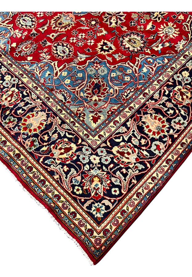 Corner detail of Persian Najafabad rug, French blue spandrel meeting navy floral border and rose red field