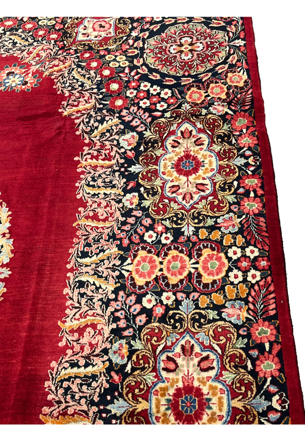 Border close-up of antique signed Moud rug, deep navy ground with red and gold rosettes, dense workshop drawing