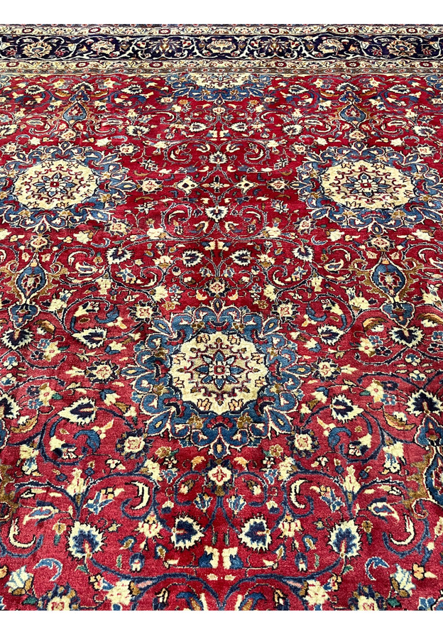 Midfield detail Persian Isfahan rug, ivory rosette discs floating on deep red ground with slate blue scrolling vinework, authentic hand-knotted