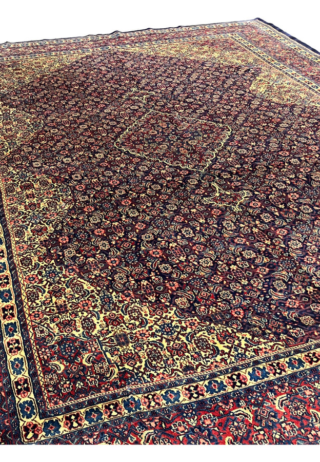 Angled corner view of 10x15 Persian Sarough rug, navy field with boteh and dense lattice, never used handmade for formal living room