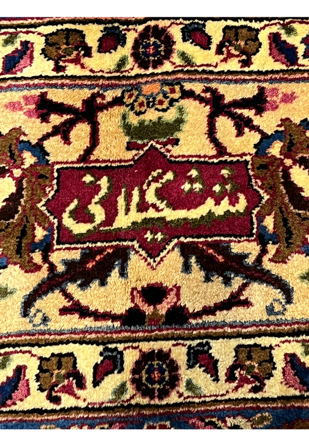 Closeup of Shash-Kalani signature Persian Mashad rug, woven Farsi script on red cartouche framed by gold border, master signed