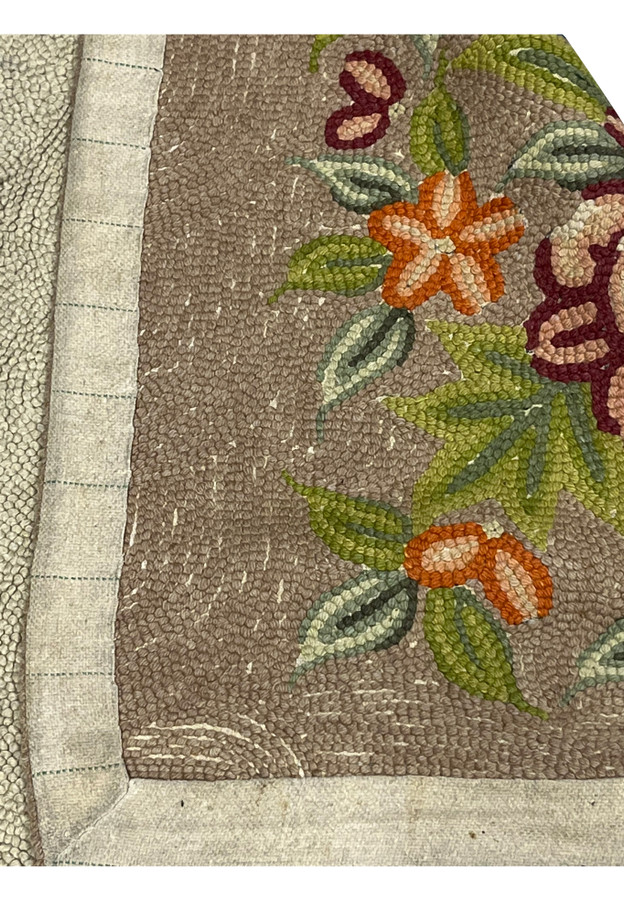 Backside corner of hand-hooked rug showing the cotton base fabric and bound cloth tape edge
