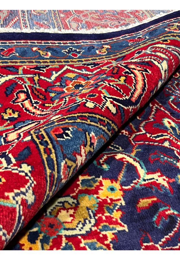 Rolled Persian Mahal rug showing navy field, red border, and dense hand-knotted wool pile