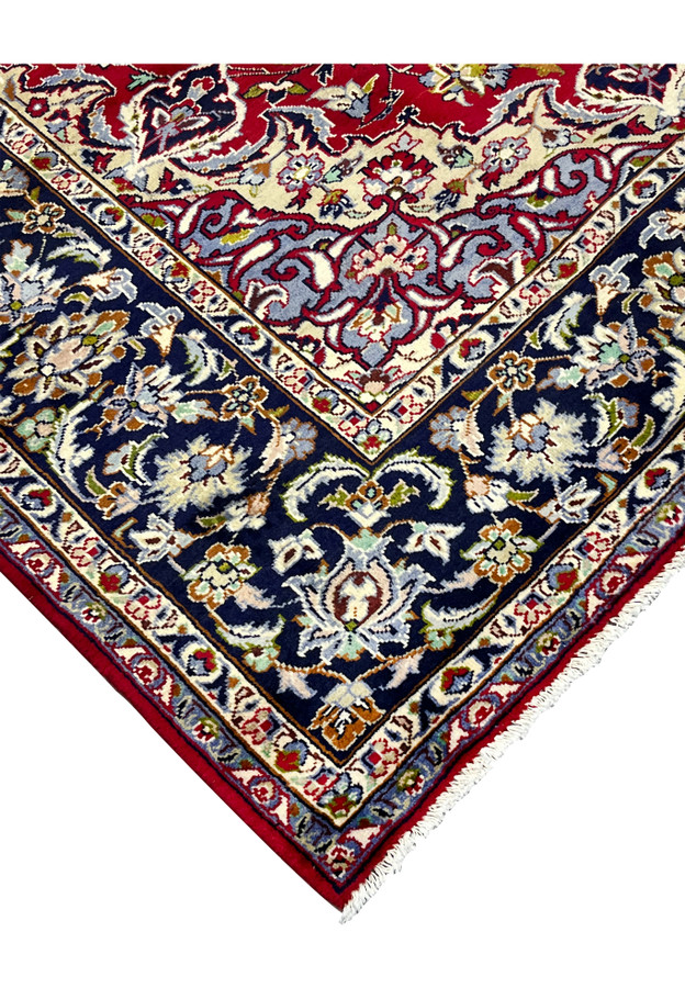 Corner edge of Persian Najafabad rug with ivory inner guard border and navy palmette main border, hand-knotted wool