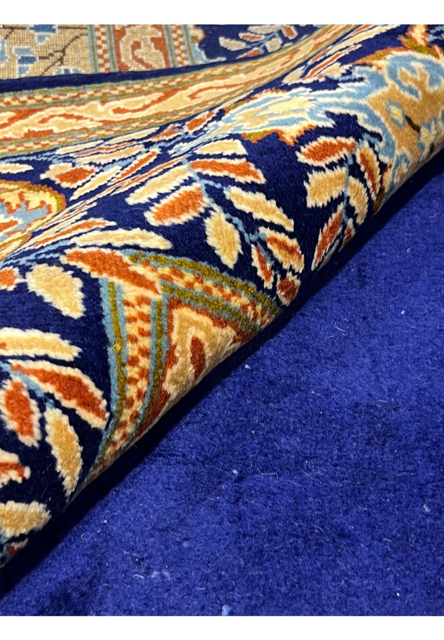 Rolled view of palace-size Persian Yazd rug showing wool pile depth and finely drawn navy border with floral detail