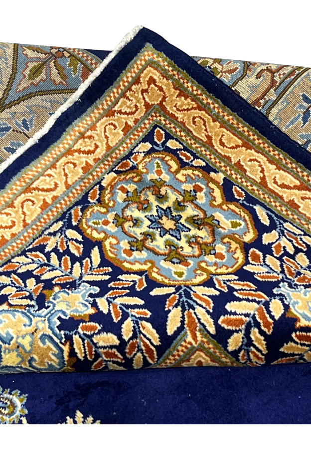 Folded edge of Persian Yazd rug showing reverse weave clarity, ivory cotton fringe and crisp navy and rust selvages