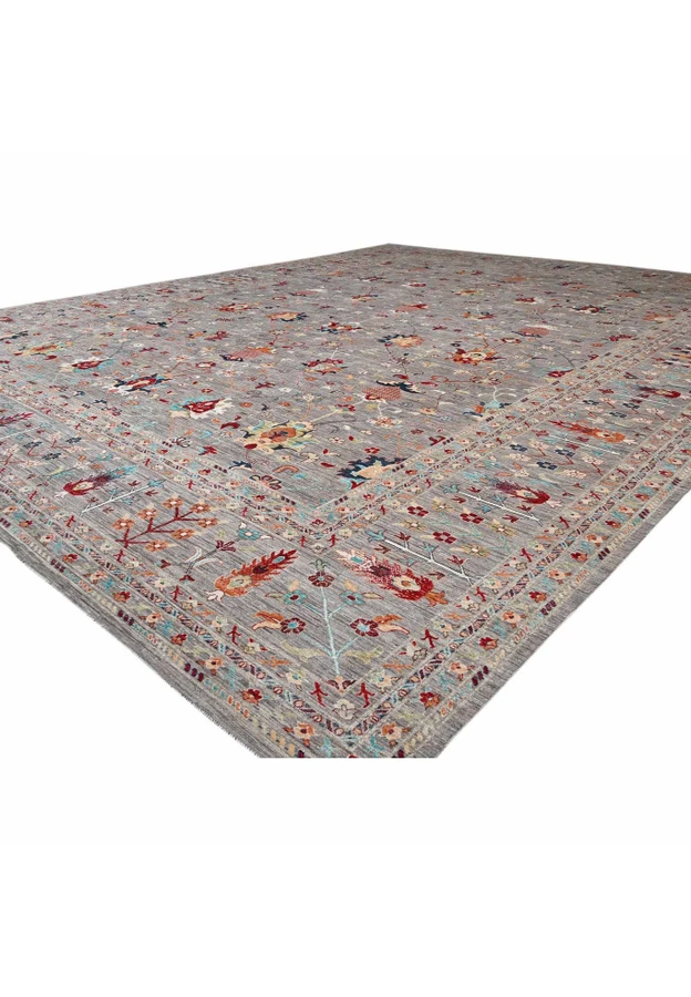 Angled view of the oversize Afghan Sultani showing soft grey ground and colorful palmette lattice across the field