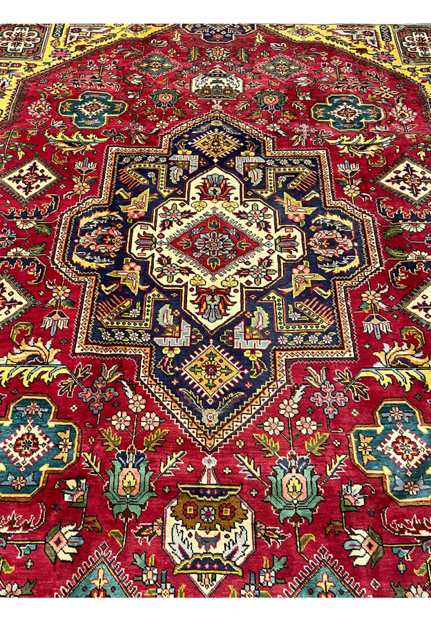 Midfield of the red Tabriz showing teal cruciform medallions and dense floral filler around the center