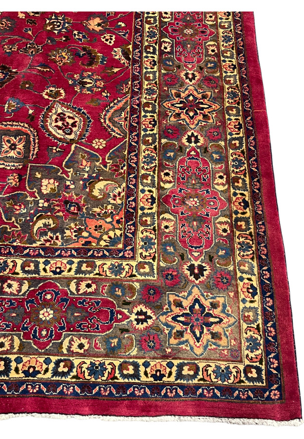 Taupe and grey corner border of the Mashad rug filled with eight-point stars and rosettes