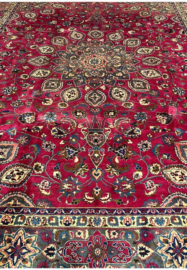 Detailed mid-field of the Mashad showing palmettes, vase motifs, and vinework on deep raspberry red