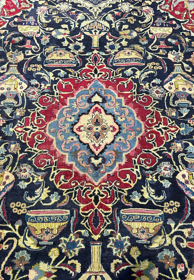 Central blue and red medallion of the Persian Kashmar Zirkhaki rug surrounded by lamps and vases