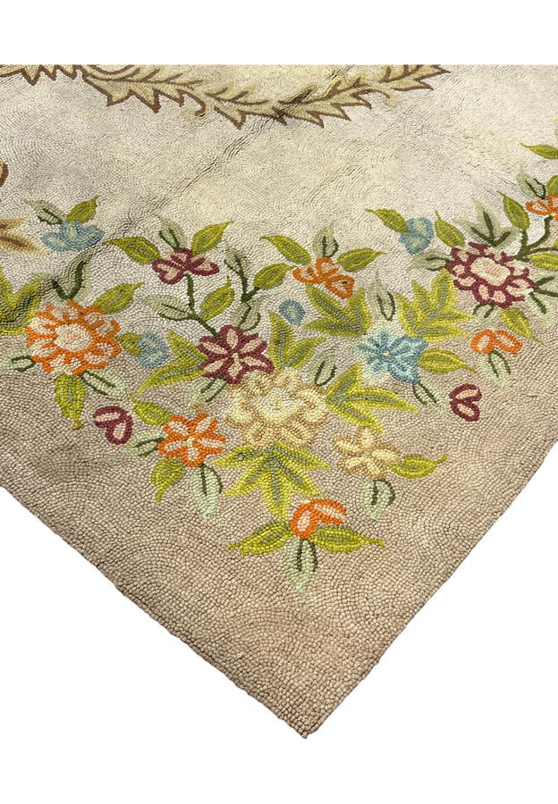 Floral garland border in pastel blooms framing the cream corner of this authentic handmade hooked rug