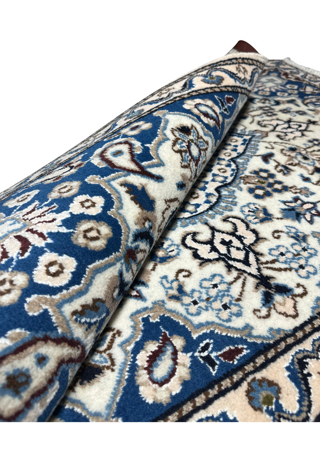 Rolled Persian Nain rug revealing its dense fine pile and rich blue and ivory palette