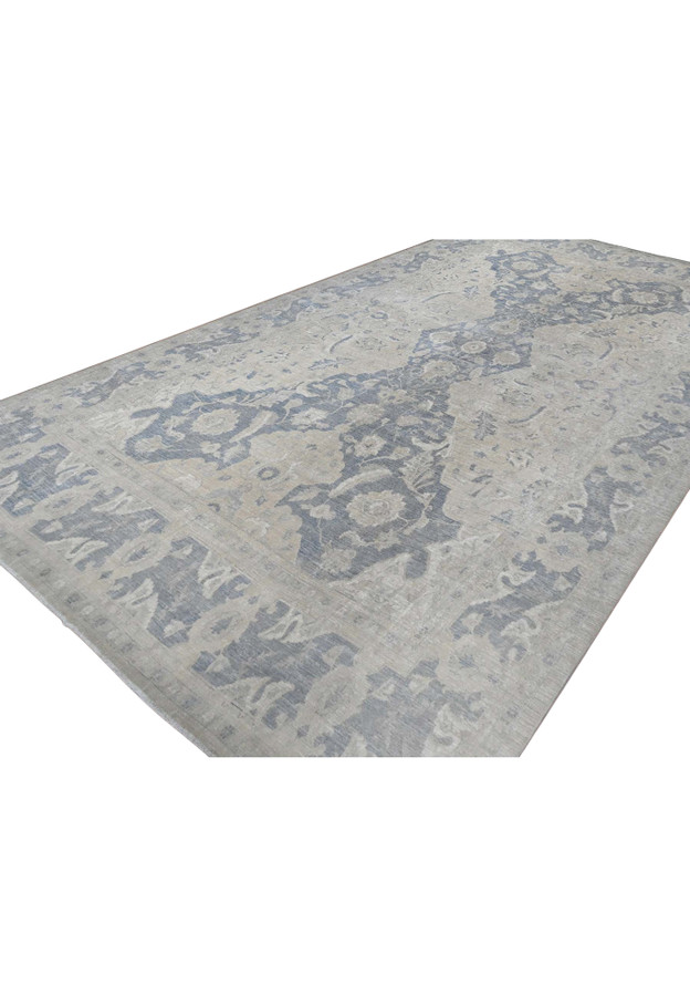 Angled view of the oversized Peshawar rug showing its washed paper-white and blue Polonaise field