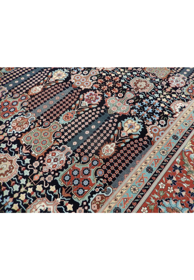 Detail of slender flowering vases and dense blossoms on navy, fine wool and silk Tabriz weave